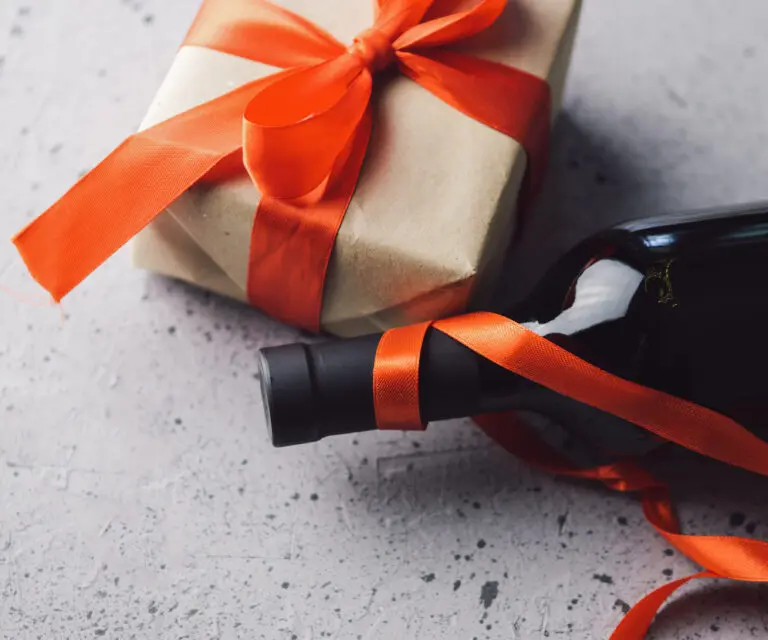 Geschenk und Weinflasche mit roter Schleife