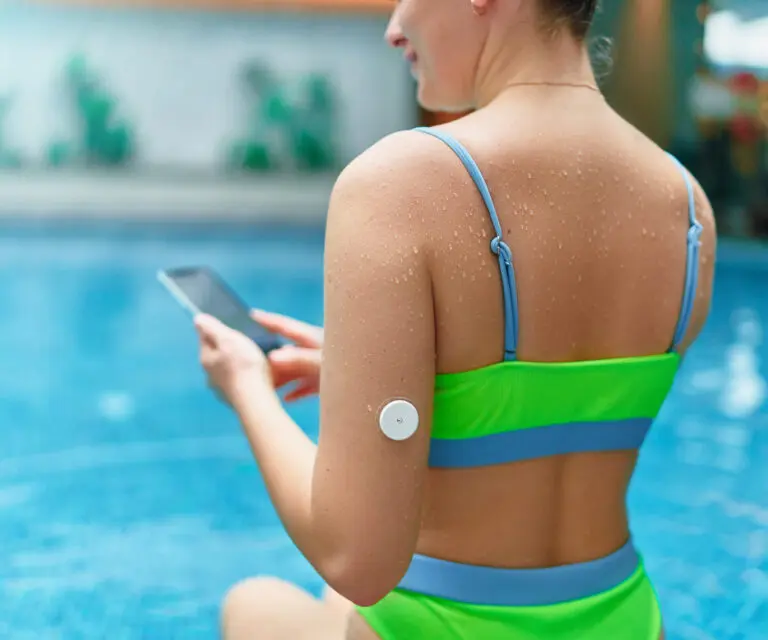 Diabetespatientin, die ihren Blutzuckerspiegel mit einem Sensor im Schwimmbad überwacht